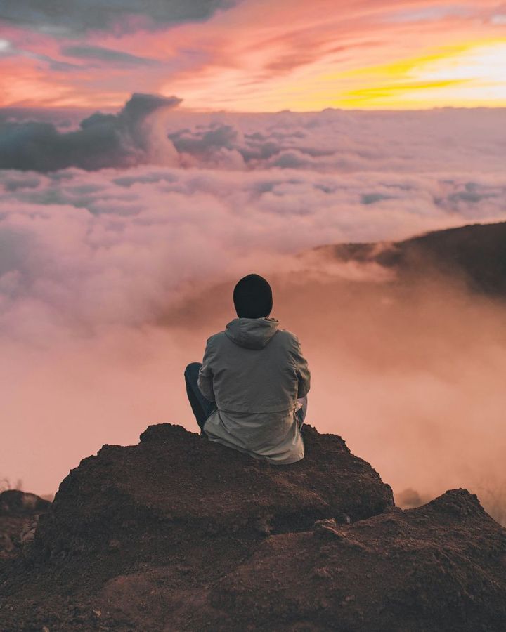 Homme contemplant un coucher de soleil au-dessus des nuages, symbole du traumatisme et de la reconnexion intérieure